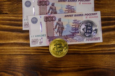 Ahşap arka planda altın ve gümüş Bitcoins ve 500 Rus ruble faturaları