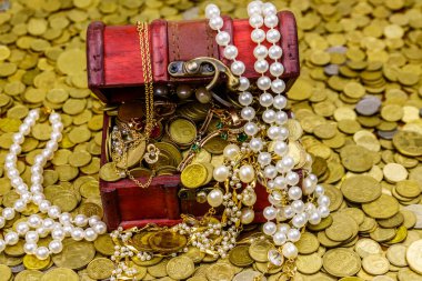 Altın sikke ve mücevherlerle dolu eski bir hazine sandığı.