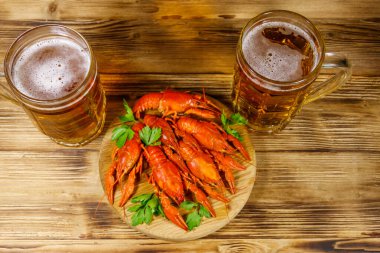 Haşlanmış kerevit ve tahta bir masada iki kupa bira.