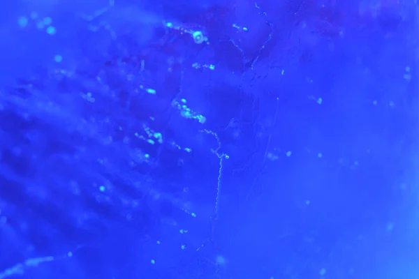 Aydınlatılmış mavi buz dokusunun içinde hava kabarcıkları olan soyut arkaplanı