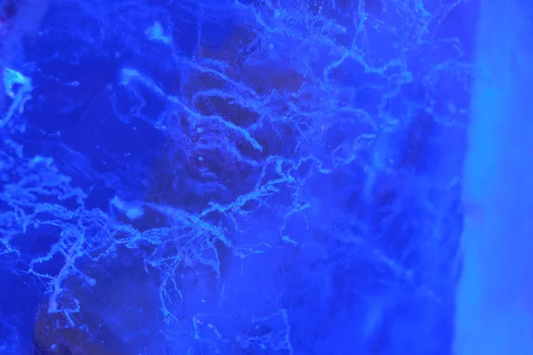 Abstrakt bakgrund belyst blå is struktur med sprickor och bubblor inuti — Stockfoto