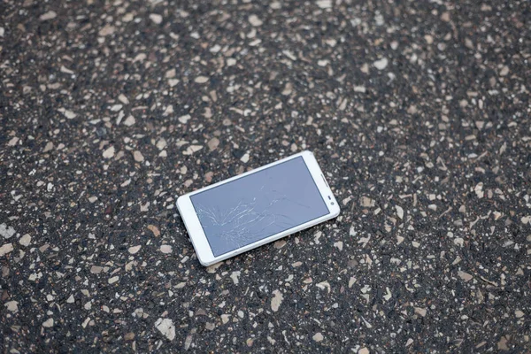 Телефон со сломанным экраном лежит на улице — стоковое фото