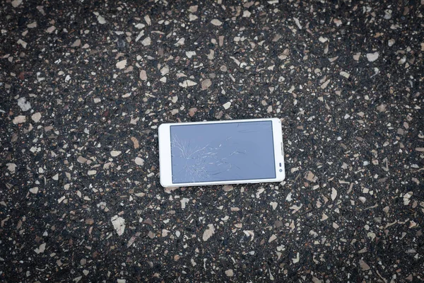 Телефон со сломанным экраном лежит на улице — стоковое фото