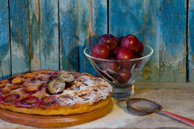 Kuru üzümlü kek ile pudra şekeri, yer süzgeci, Erik, eski ahşap arka plan ile piala