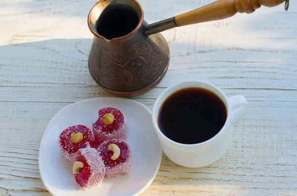 Coffee Mug, Turkish delight with nuts and copper Cezve on a light wooden table in the sunlight — Stock Photo, Image