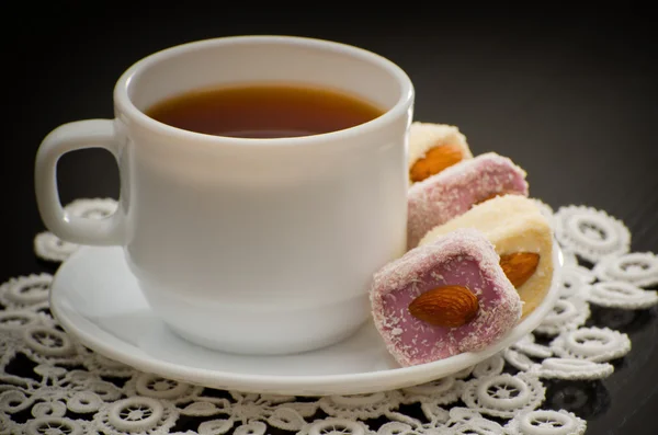 Mug of tea and Turkish delight with nuts on a plate, close-up, black background — Stock Photo, Image