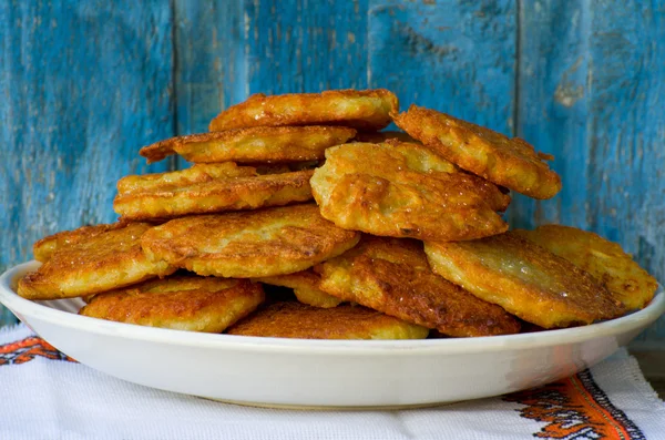 Plate with potato pancakes, blue wood background, close-up — Stock Photo, Image