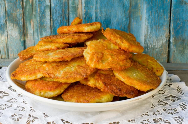 Großer Teller Kartoffelpuffer auf Serviette, blauer Holzhintergrund — Stockfoto