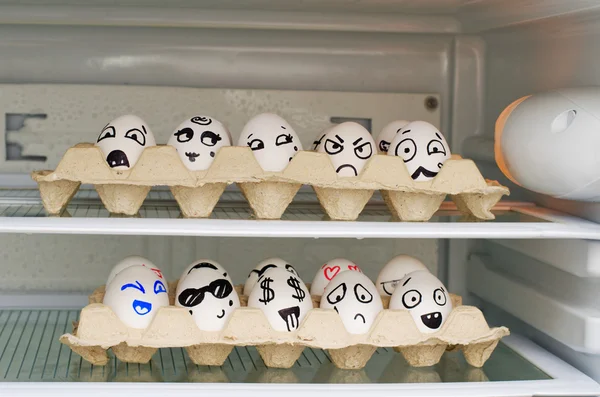 Два лотки з розфарбованими посмішками на яйцях на полицях холодильника — стокове фото