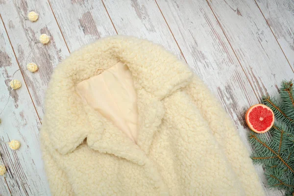 Milky fur coat on a wooden background, spruce branch. Fashion concept. Top view — Stock Photo, Image