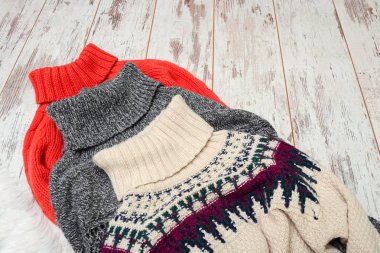 Ahşap arka plan üzerinde boyun için üç sıcak kazak. Moda kavramı.