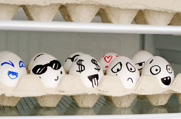 Huevos con emociones pintadas en una bandeja en un estante en el refrigerador — Foto de Stock