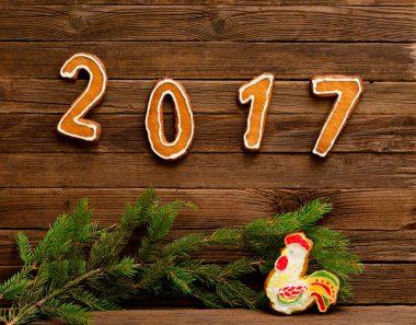 Yeni yıl kavramı. Şekil 2017 ve gingerbread, köknar dalı ahşap arka plan üzerinde gelen horoz.