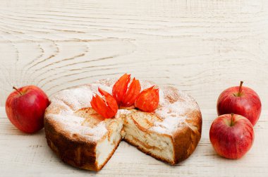 Elmalı turta ve ahşap masa lambası üzerinde üç olgun elma