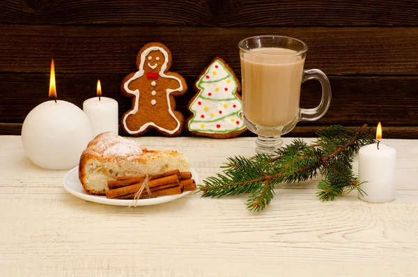 Christmas installation. Fir branch, gingerbread, pots, cake and candles on wooden background