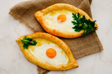 İki khachapuri yumurta ve maydanoz üzerinde çul, üstten görünüm