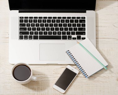 Bir dizüstü bilgisayar klavye, akıllı telefon, bir defter bir kalem ve bir fincan kahve ile Üstten Görünüm