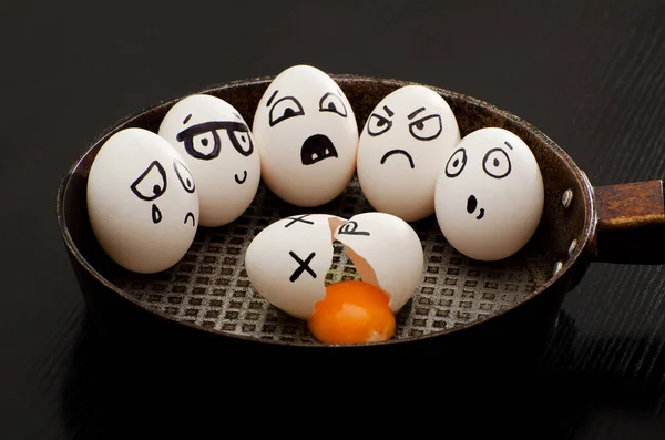 Huevo roto en una sartén rodeado de huevos enteros con diferentes emociones — Foto de Stock