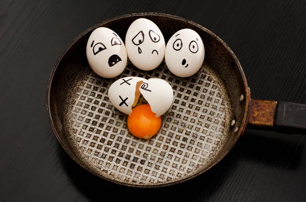 Tres huevos con emociones, huevo roto en el centro de la sartén, mesa negra — Foto de Stock