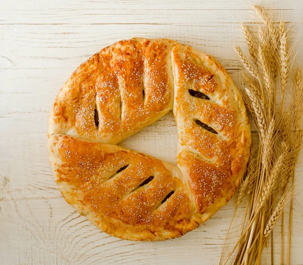 Runde Torte mit Sesam auf hellem Holzgrund, Ähren — Stockfoto