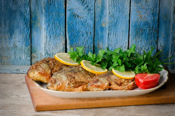 Жареная рыба с лимоном и петрушкой на синем деревянном фоне — стоковое фото