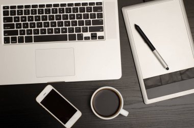 Grafik tablet kalem, bazı dizüstü bilgisayar, telefon ve coffeee üzerinde siyah ahşap masa, yakın çekim