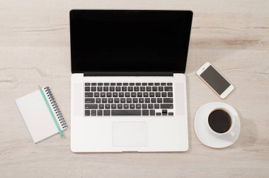 Bir dizüstü bilgisayar, akıllı telefon, bir defter bir kalem ve bir fincan kahve ile Üstten Görünüm