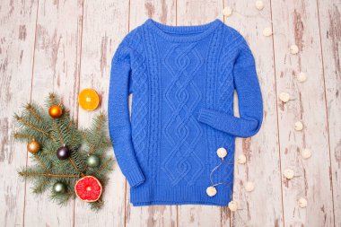 Ahşap bir zemin üzerine mavi kazak. Narenciye, köknar dalı garland. Moda kavramı, üstten görünüm