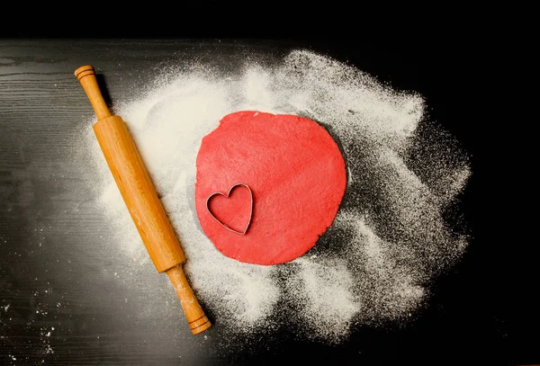 Piros tésztát formában kivágott szívek és a liszt, a fekete tábla, egy sodrófa. szemközti nézet — Stock Fotó