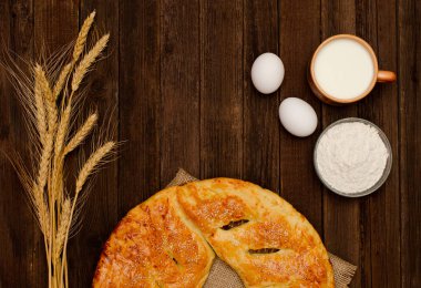 Pasta, pişirme, kulakları buğday için malzemeler ve süt ahşap arka plan üzerine bir fincan. Metin için yer.