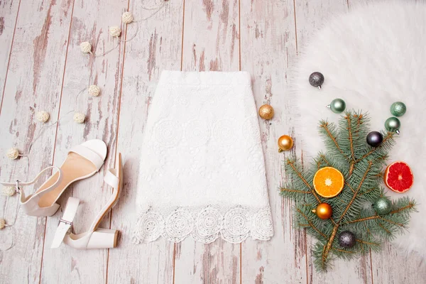 Saia branca rendada e sapatos brancos em um fundo de madeira, bolas de Natal no ramo de abeto. Conceito na moda, vista superior — Fotografia de Stock