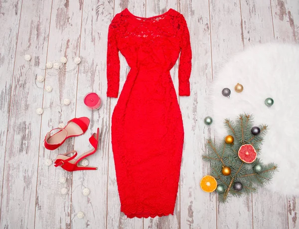Vestido de renda elegante vermelho, sapatos vermelhos em um fundo de madeira, ramo de abeto com ornamentos e cítricos. conceito de moda — Fotografia de Stock