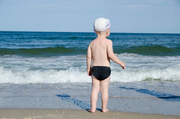 Küçük sarışın çocuk sahilde dalgalar arka ve seyir