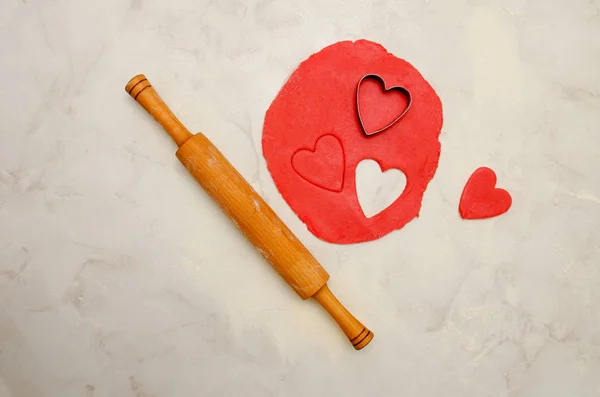 Kırmızı hamur ile bir oklava ve beyaz bir tablo kesip kalpleri. Üstten Görünüm, metin için yer — Stok fotoğraf