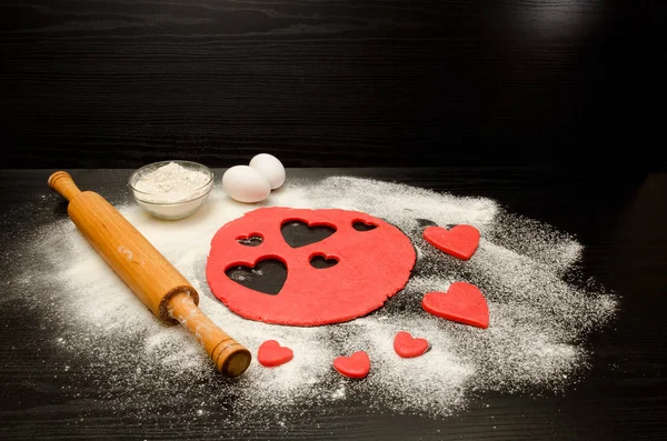 Kırmızı hamur, Kalpler, un, yumurta ve merdane siyah bir arka plan, metin için yer kesip — Stok fotoğraf