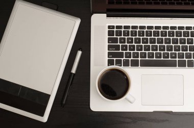 Grafik tablet kalem, defter ve kahve siyah ahşap bir masa üzerinde bir parçası ile yakın çekim