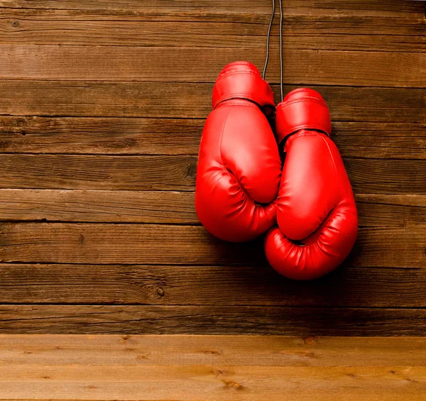 Two red boxing gloves hung on a wooden brown background, empty space — Stock Photo, Image