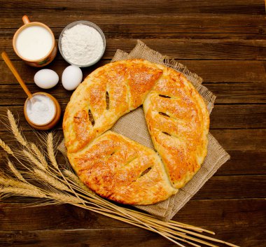 Çuval bezi, pişirme, buğday kulakları ve bir bardak süt ahşap arka plan üzerinde için malzemeler üzerinde pasta