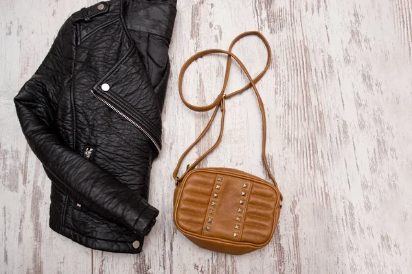 ファッションの概念。黒革のジャケットと木製の背景に茶色のハンドバッグ。上面図、テキスト用のスペース — ストック写真