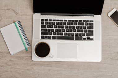 Bir dizüstü bilgisayar, akıllı telefon, bir defter bir kalem ve bir fincan kahve ile Üstten Görünüm