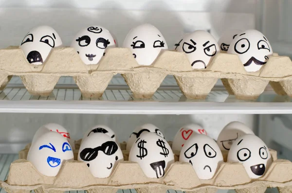 Два лотки з розфарбованими посмішками на яйцях на полицях холодильника, крупним планом — стокове фото