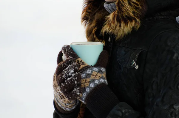 Chica en guantes abrazó su taza de té, fondo blanco nevado —  Fotos de Stock