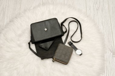 Bir sızıntı dışarı-in onun telefon, gri bir çanta ve bir saat açık siyah çanta. Arka plan, üstten görünüm üzerinde beyaz kürk. moda kavramı