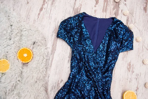 Синее платье в блёстках и апельсинах на сером искусственном мехе, деревянном фоне. Модная концепция, вид сверху — стоковое фото