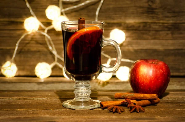 Εσωτερικη κούπα ζεστό κρασί με μπαχαρικά. Apple, ραβδιά κανέλας και το γλυκάνισο σε ένα ξύλινο τραπέζι, φανάρια στο παρασκήνιο — Φωτογραφία Αρχείου