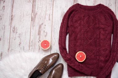 Kestane rengi örme kazak, kahverengi deri ayakkabılar, greyfurt yarım kesilmiş. Ahşap arka plan, metin için yer. Moda kavramı. Üstten Görünüm