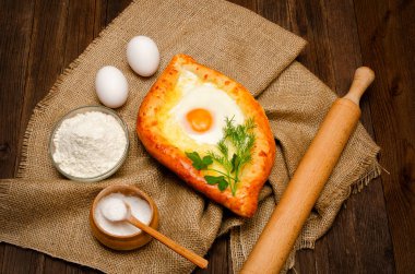 Khachapuri yas, tuz, un ve yumurta üzerinde ahşap masa üzerinde yumurta ile
