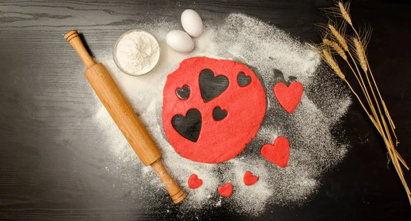 Kırmızı hamur, Kalpler, un, yumurta ve merdane siyah bir arka plan, metin için yer kesip — Stok fotoğraf