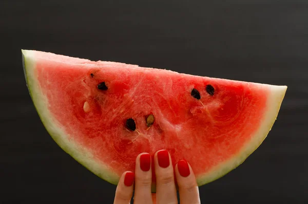 Halvcirkel med mogen vattenmelon i kvinnliga händer på svart bakgrund, utrymme för text — Stockfoto