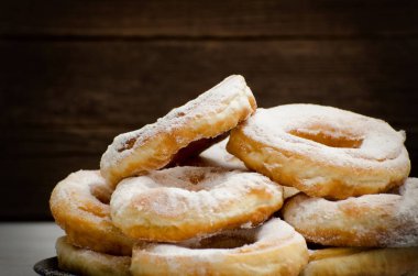 Çörek pudra şekeri, koyu ahşap arka plan ile serpilir. Yakın çekim, yan görünüm